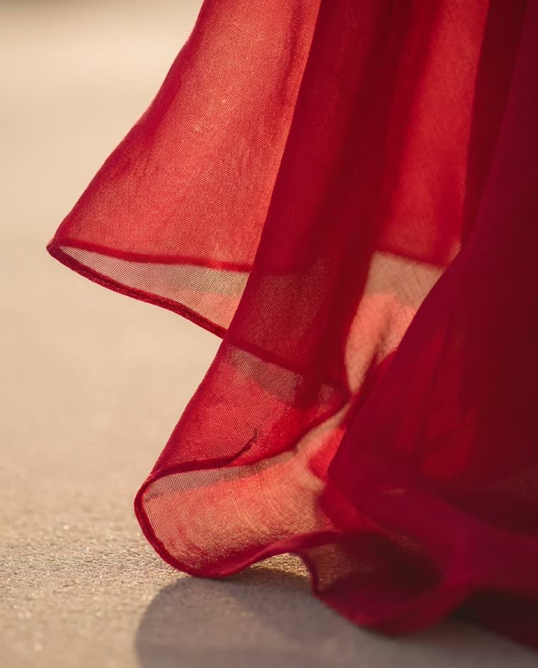 Extreme close-up of red chiffon hem and folds, weave and translucency visible